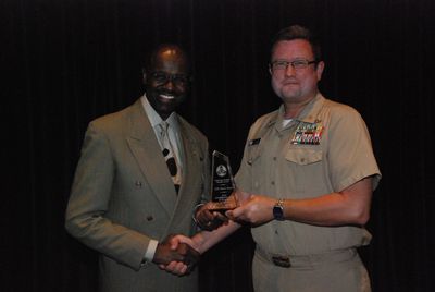 Navy award presentation ceremony with trophy and handshake