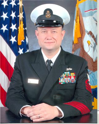 Formal seated Navy portrait with flags in background
