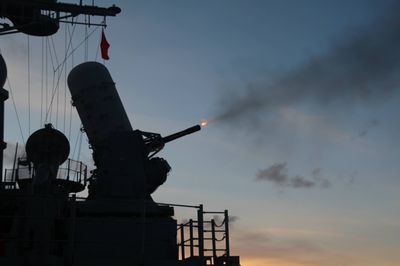 Close-In Weapon System (CIWS) firing during a live-fire exercise at dusk