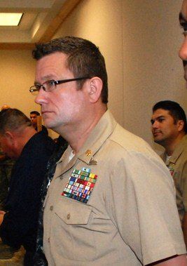 Between meetings in an institutional hallway, tan service uniform with ribbons