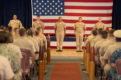 Formal assembly on stage in front of the colors