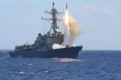 U.S. Navy destroyer missile launch with bright flame trail at sea