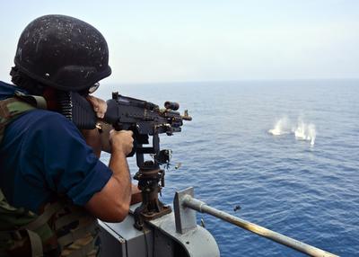 Navy gunner operating a mounted machine gun at sea