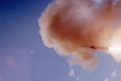 Dramatic high-altitude rocket or missile plume against a clear blue sky