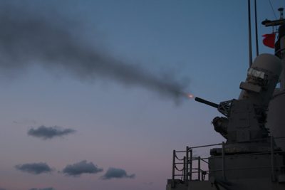 Naval vessel underway at twilight during live fire