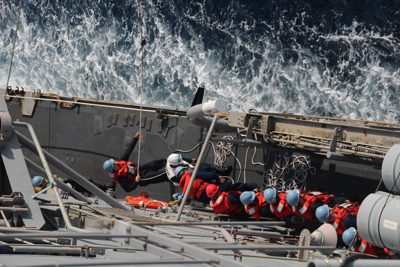 Sailors conducting deck work in heavy weather